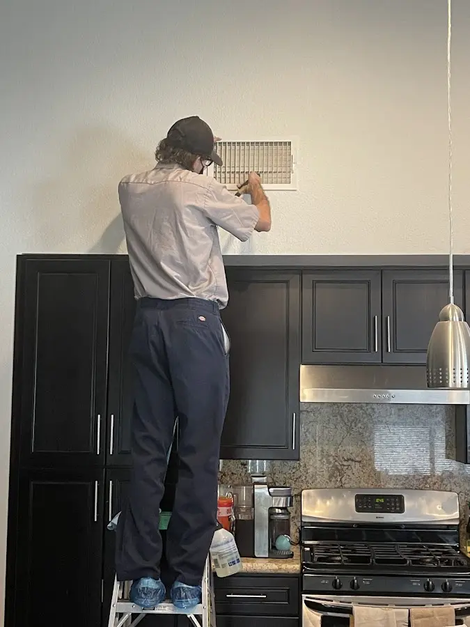 Technician inspecting an air vent during HVAC service in Guntersville